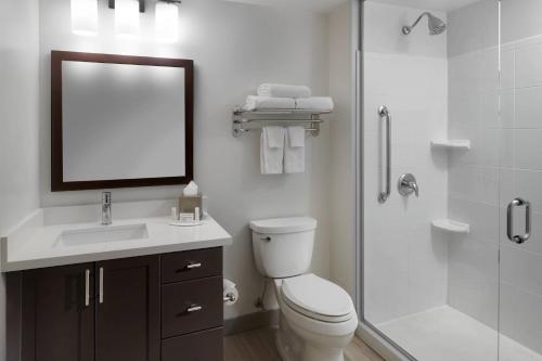 a bathroom with a toilet and a shower with a mirror at TownePlace Suites by Marriott Mississauga-Airport Corporate Centre in Mississauga