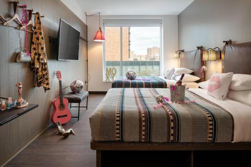Un dormitorio con 2 camas y una guitarra. en Moxy Austin - University, en Austin