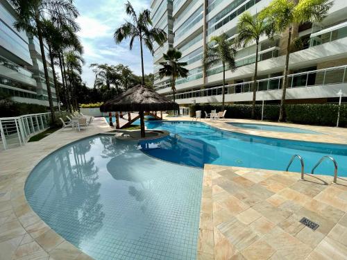 a swimming pool with a umbrella and a building at Apartamento familiar em Riviera de São Lourenço Módulo 8 in Bertioga