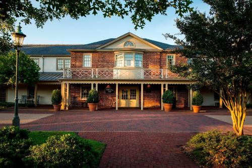 a large brick house with a balcony on a driveway at Williamsburg Lodge, Autograph Collection in Williamsburg