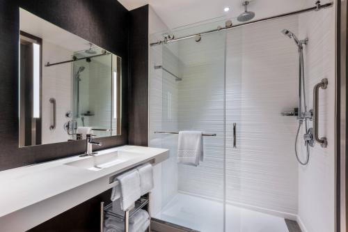a bathroom with a sink and a shower at AC Hotel by Marriott Charlotte City Center in Charlotte