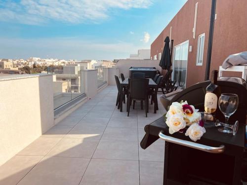 un balcón con una mesa con copas de vino y flores en The Hazel penthouse with private jacuzzi, en Birkirkara