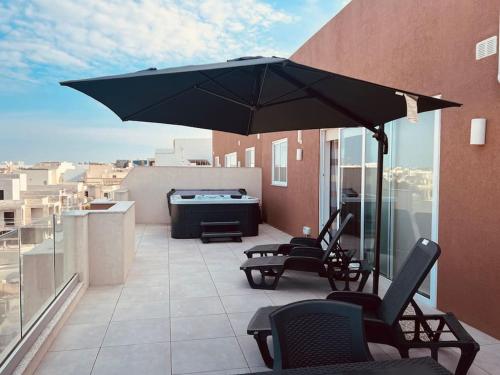um pátio com cadeiras e um guarda-sol numa varanda em The Hazel penthouse with private jacuzzi em Birkirkara