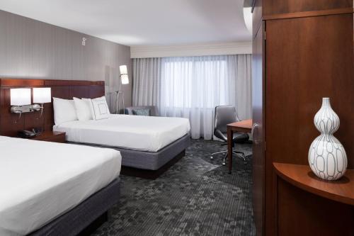 a hotel room with two beds and a desk at Courtyard by Marriott West Orange in West Orange