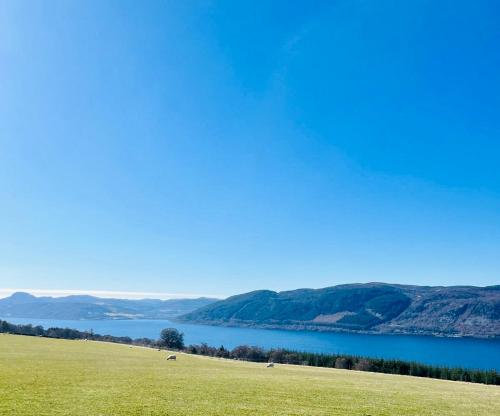 a green field with a view of a body of water at 1 Loch Ness Heights in Inverness