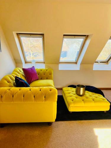 two yellow couches sitting in a room with windows at 1 Loch Ness Heights in Inverness