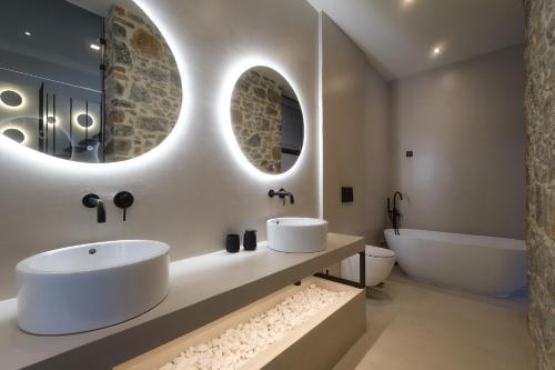 a bathroom with two sinks and a tub and mirror at Zaira Hotel in Skála Loutrón