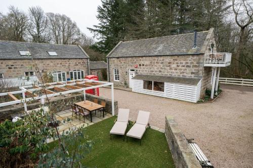 a patio with two chairs and a table and a building at Ranch House Cottage, Pet Friendly Stay, Inverurie in Thainstone