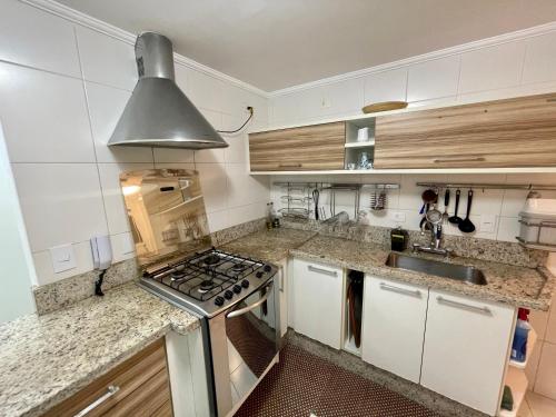 a kitchen with a stove top oven next to a sink at Apartamento familiar em Riviera de São Lourenço Módulo 8 in Bertioga