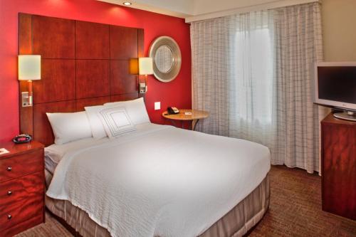 プレスコットにあるResidence Inn Prescottの大型ベッドとテレビが備わるホテルルームです。