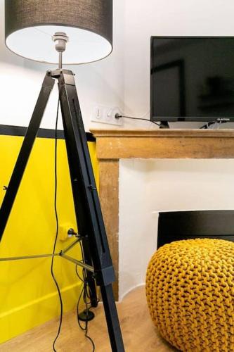 un tripod avec une lampe à côté d'une télévision et d'une chaise dans l'établissement Le Lemon : au coeur du centre historique, à Dijon