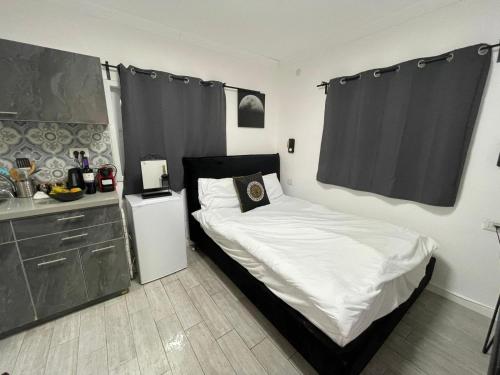 Dormitorio pequeño con cama con cabecero negro en דירת סטודיו יפיפיה על גג ומרפסת שמש ברחוב הירקון, en Tel Aviv