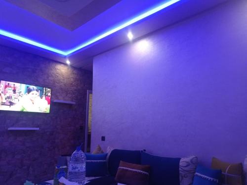 Saad apprtemnt في أغادير: غرفة بها أريكة وتلفزيون على الحائط