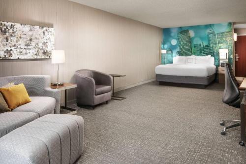 a hotel room with a bed and a couch and chair at Courtyard Indianapolis at the Capitol in Indianapolis