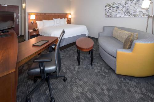 a hotel room with a bed and a couch and a desk at Courtyard by Marriott Albany in Albany