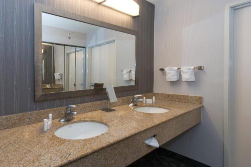 a bathroom with two sinks and a large mirror at Courtyard by Marriott Albany in Albany