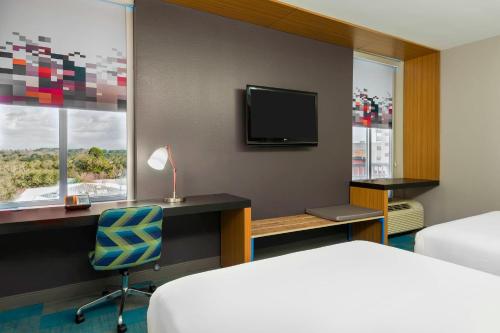 Habitación de hotel con cama, escritorio y TV. en Aloft Tallahassee Downtown en Tallahassee