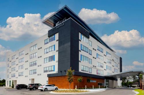 a hotel building with cars parked in a parking lot at Aloft Savannah Airport in Savannah