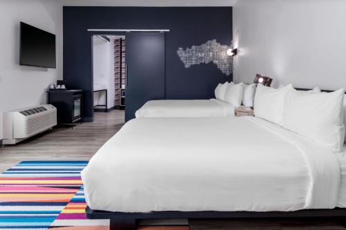 a bedroom with two white beds and a blue wall at Aloft Savannah Airport in Savannah
