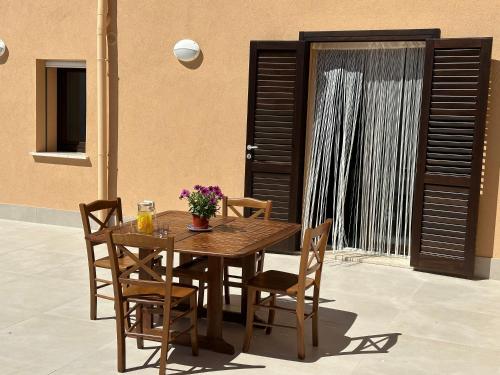 een houten tafel en stoelen met bloemen op een patio bij Villa FIORENZA - 100 mt dal Mare in Castellammare del Golfo