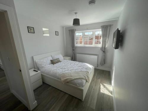 a white bedroom with a bed and a window at DaisyChain Getaways at Chaney Rd in Wivenhoe