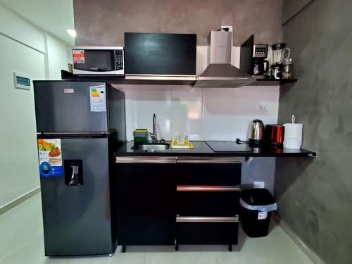 a small kitchen with a refrigerator and a microwave at Bellini Suites Apartments in Santa Cruz de la Sierra