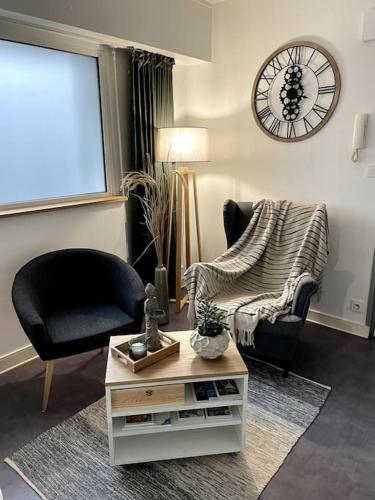 ein Wohnzimmer mit einem Stuhl, einem Tisch und einer Uhr in der Unterkunft Charmant Appartement Vannes Centre 30m2 in Vannes