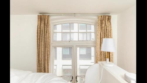 Dormitorio con ventana, cama y lámpara en Unique Character Filled, East London Flat en Londres