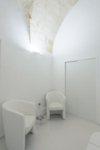 a white room with a chair and a mirror at Vittorio Veneto Matera Luxury Rooms in Matera