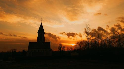 a silhouette of a church with a sunset in the background at La Bohème in Paissy