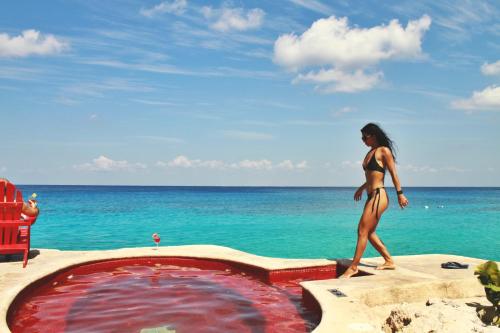 a woman in a bikini walking next to a swimming pool at Hotel B Cozumel in Cozumel