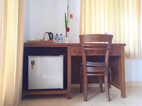 a wooden desk with a chair next to a table with a microwave at Tanah Semujan Ubud in Ubud