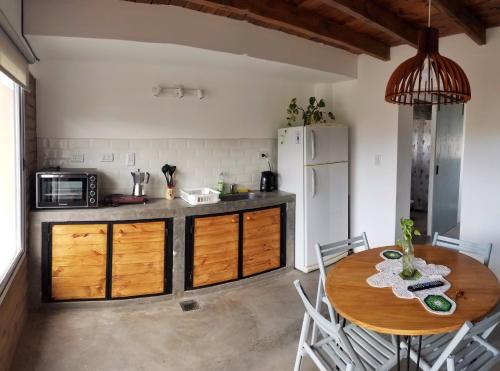 eine Küche mit einem Holztisch und einem weißen Kühlschrank in der Unterkunft Malvón in Cafayate
