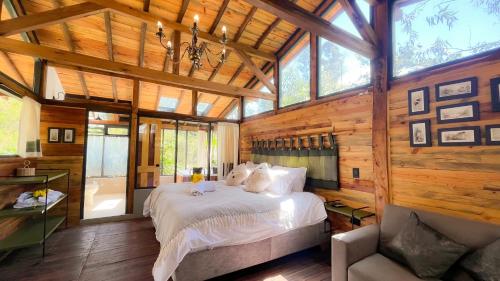1 dormitorio con 1 cama grande en una habitación con paredes de madera en Suite Cabaña Cantodeagua-Jacuzzi, en Villa de Leyva