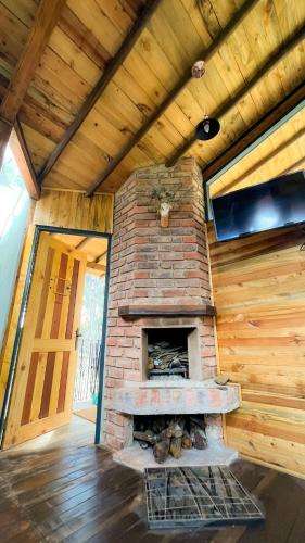 a brick fireplace in a room with a wooden ceiling at "Suite Cabaña Cantodeagua - Jacuzzi -Refugio en Reserva Natural Urbana - Villa de Leyva" in Villa de Leyva