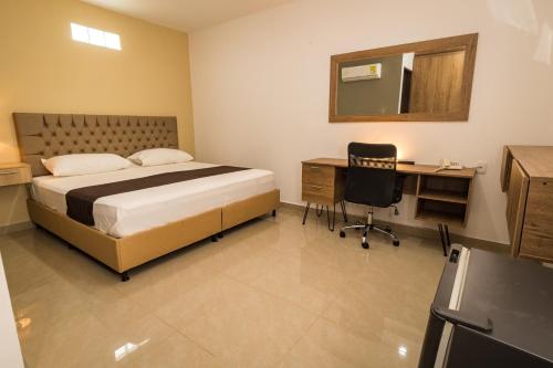 une chambre avec un lit, un bureau et un miroir dans l'établissement Genesis Hotel, à Sincelejo