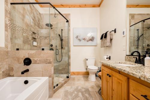 een badkamer met een douche, een bad en een toilet bij Modern Mountain Retreat in Victor