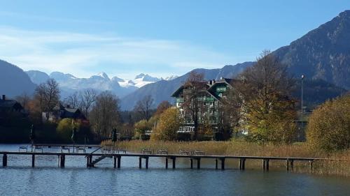 a dock on a lake with a house and mountains at Ferienwohnung Amelie in Sattendorf
