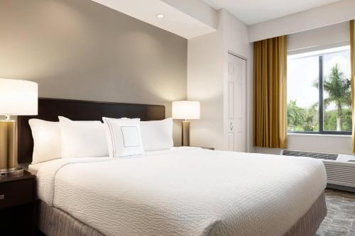 a hotel room with a large bed and a window at Springhill Suites by Marriott West Palm Beach I-95 in West Palm Beach