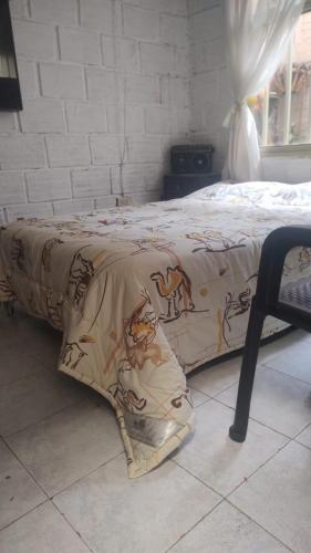 Una cama con una manta encima. en HOSPEDAJE OK en Salento