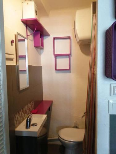 La salle de bains est pourvue de toilettes, d'un lavabo et de fenêtres. dans l'établissement Appartement pas cher en Bord de mer avec Piscine, à Canet