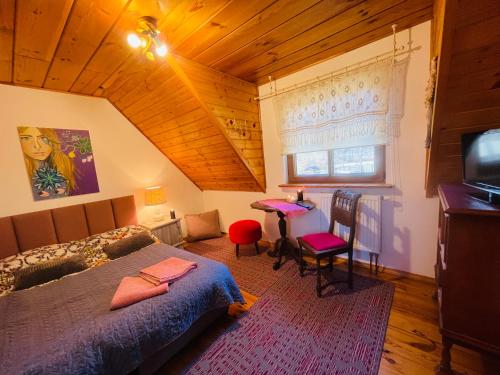 Dormitorio con cama, escritorio y TV en Siedlisko Zatoka, en Augustów