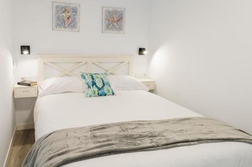 een slaapkamer met een wit bed en twee foto's aan de muur bij El rinconcito de la playa, parking incluido in Sanxenxo