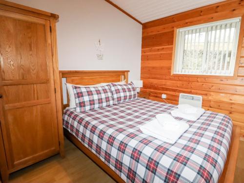 um pequeno quarto com uma cama com um cobertor xadrez em Watersview Lodge em Leek