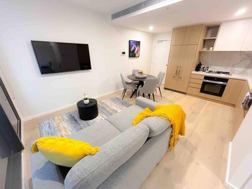 a living room with a gray couch and a kitchen at Moonee Ponds Living on Young - 205 in Melbourne