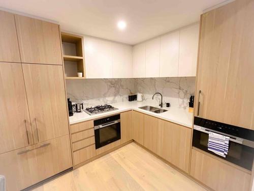 a kitchen with wooden cabinets and a sink and a stove at Moonee Ponds Living on Young - 205 in Melbourne