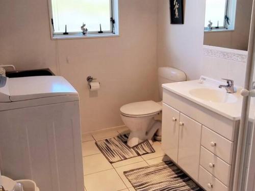 a bathroom with a toilet and a sink and a mirror at 1 bdrm Beach Apartment Papamoa in Papamoa