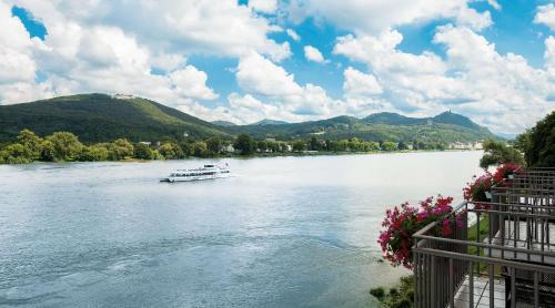a boat on a river with mountains in the background at Rheinhotel Dreesen in Bonn