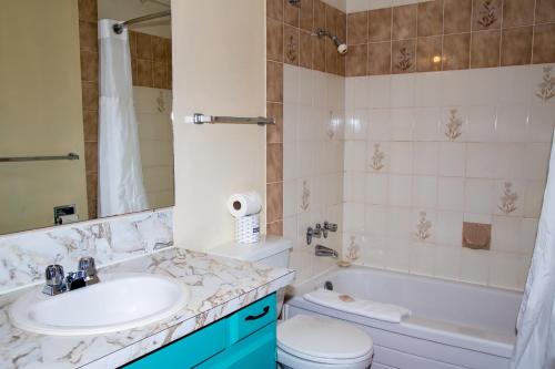 een badkamer met een wastafel, een toilet en een bad bij Bowmont Motel in Penticton