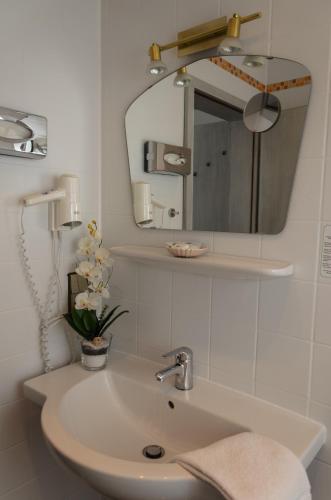 a bathroom sink with a mirror and a vase of flowers at Hotel Rheingraf in Kamp-Bornhofen